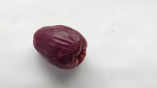 The hand places the large rose apple, or malay apple, or Syzygium malaccense, or jambu bol, or red guava, or jamaica guava