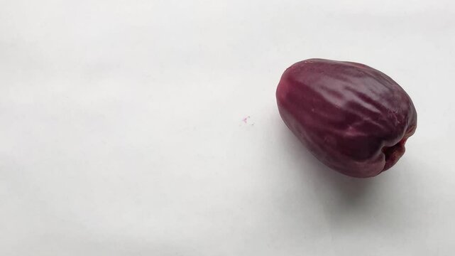 The hand places the large rose apple, or malay apple, or Syzygium malaccense, or jambu bol, or red guava, or jamaica guava