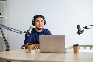 Male Recording an Audio Podcast While Using a Microphone, Headphones and Laptop