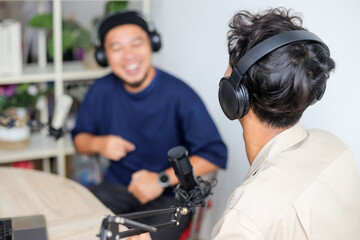 Male Podcaster in Headphones Interviewing Man Guest using Microphone in Broadcasting Studio