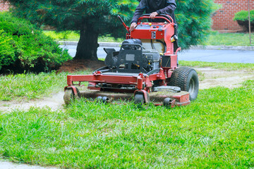 Obraz premium Riding lawn mower is efficiently trimming grass in well maintained residential garden