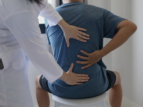Asian male patient receives physical therapy with a physical therapist specializing in pain management in a hospital