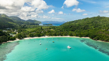 Beach bordered by green trees and clear blue sea. Port Launay Beach. Seychelles.