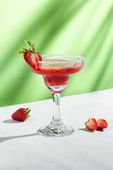 Refreshing Strawberry daiquiri Cocktail in a Glass with Sugar Rim and Garnish on green background
