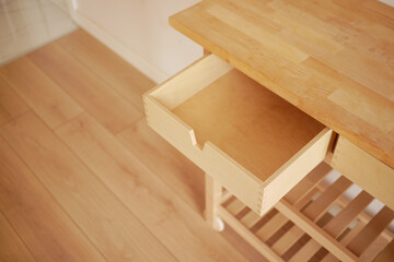 Wood kitchen drawer partially open on a light floor