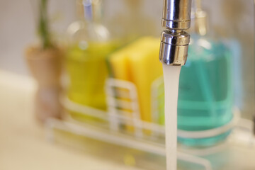 Water flowing from a modern kitchen faucet at home