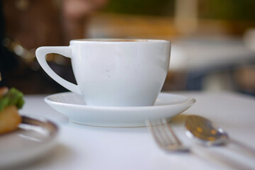Ceramic cup on a white table at morning cafe