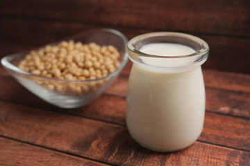 Creamy soy milk with soybeans on wooden table