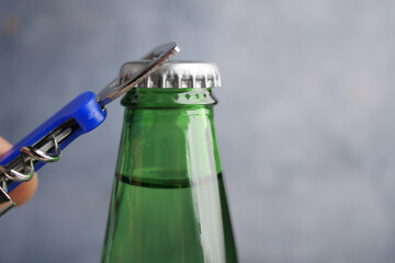 Opening a green glass bottle with a bottle opener