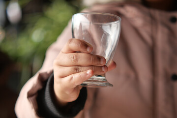 Child holding a clear glass cup in cozy setting