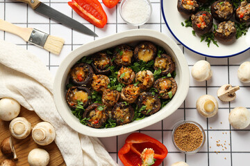 Stuffed mushrooms, towel, vegetables and spices on light background, top view