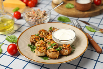 Stuffed mushrooms on plate, sauce and ingredients on light background, close up