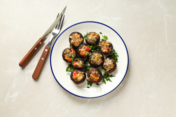 Stuffed mushrooms on plate and cutlery on light background, top view