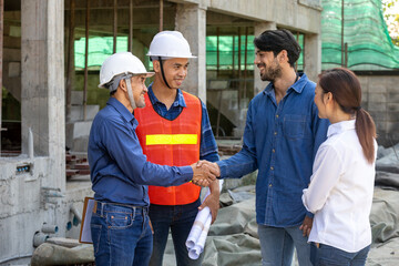 Newly wed couple is handshaking with engineering contractor at the under construction house to inspect building progress and quality control for home ownership and real estate development