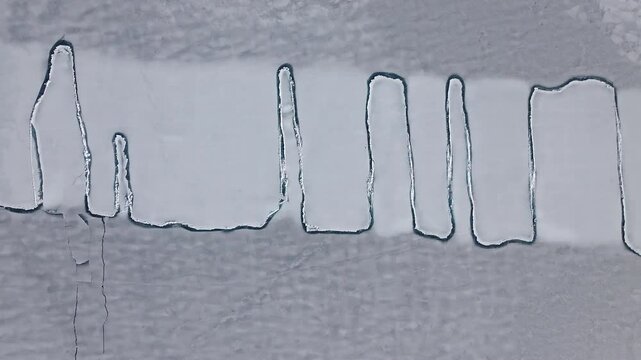 Aerial view of intricate pattern of cracks on the icy surface of a frozen lake