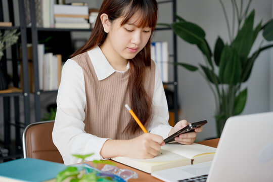 Asian girl student doing exam hand holding pencil writing answer in university classroom education high school or university student taking notes while preparing for exam - Powered by Adobe