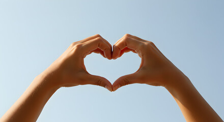 Fototapeta premium Heart Shape Hands: A Symbol of Love Against a Clear Blue Sky
