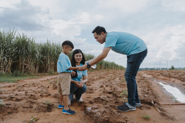 Happy family of father, mother and child are helping each other plant trees on World Warming Day at...