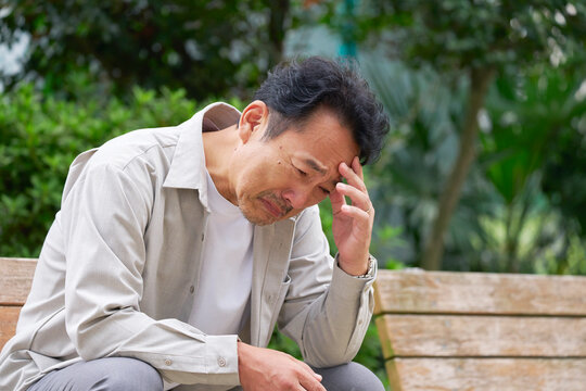 中年の男性　落ち込む　公園