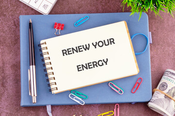 A notebook with the phrase renew your energy is placed on a table among stationery items and...