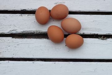 Five brown eggs on white rustic table