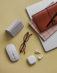 Laptop, notepad, wireless headphones, calendar on a yellow background, top view. Business, training concept