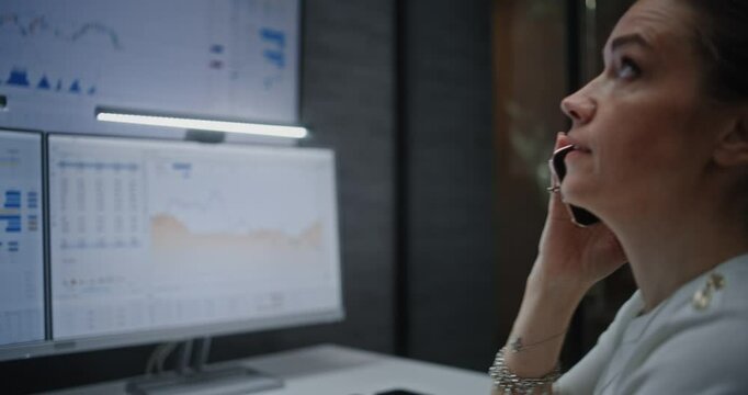 Female Stock Exchange Trader Having Phone Call, Monitoring Real-Time Stocks and Exchange Market Charts on Multi-Monitor Computer and Digital Tablet. Investment Agent Stressed About Bad Economy News.