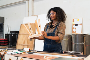 Black people, Carpenter and furniture workshop. Female carpenter assembling a wooden table in furniture factory. Woman carpenter and small business