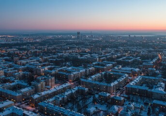 Obraz premium Snow covered city buildings and streets at dusk from an aerial view
