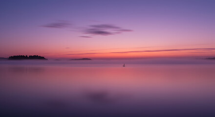 Fototapeta premium Serene Sunset over Misty Lake with Silhouetted Islands and Calm Waters
