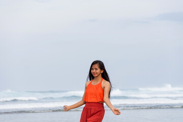 Fototapeta premium Joyful asian young woman in swimsuit dancing on ocean shore