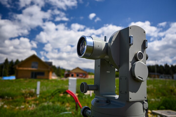 Theodolite surveying instrument measuring land for a new housing development project under a cloudy...