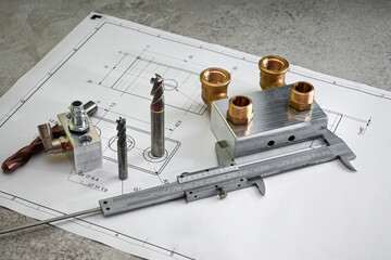 Metalworking concept showing end mills, caliper, machined parts and brass fittings lying on a...