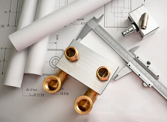 Plumbing project development with brass plumbing manifold, caliper and technical drawings lying on...