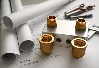 Plumbing project showing manifold, fittings, blueprint and end mills lying on a table, suggesting...