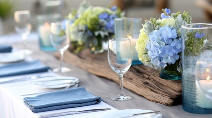 Elegant outdoor dining setup with blue floral arrangements, candles, and table settings