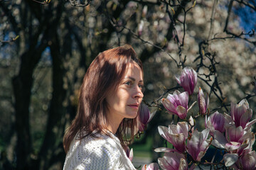 Caucasian young female enjoying spring blossoms in blooming garden