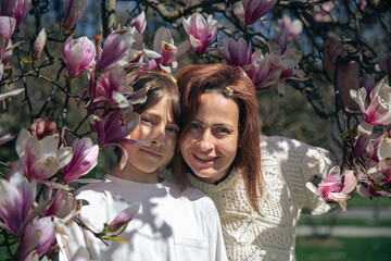 Mother and son in magnolia tree, caucasian female and male, outdoor spring scene