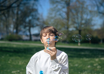 Caucasian young boy blowing bubbles in park on sunny day