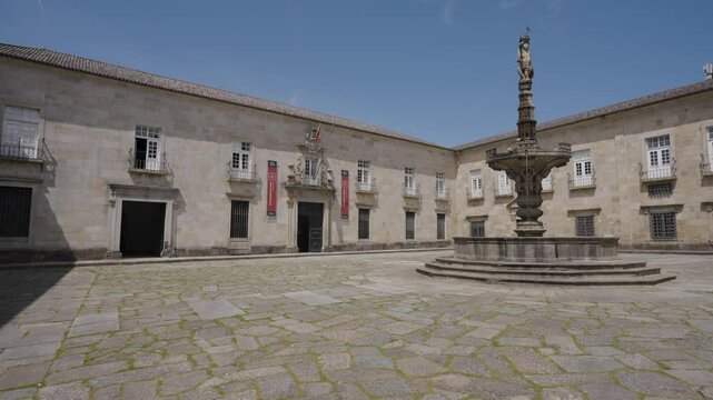 Baroque fountain crowned by a castels statue under a clear sky in front of the Reitoria University of Minho, Braga, Portugal.