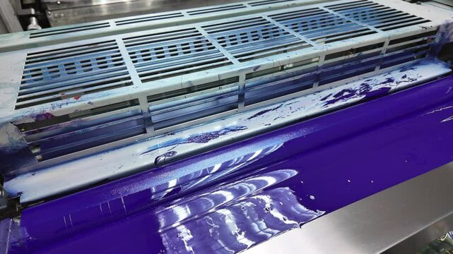 Close up of a printing press roller covered in vibrant blue ink