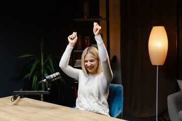 Excited female podcaster celebrating success in her home studio