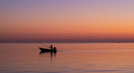 Serene Sunset Silhouette Fisherman in Small Boat at Dawn on Calm Ocean Waters