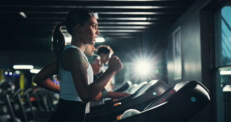 Energy, woman and running on treadmill in gym at night for agility training, speed development or...