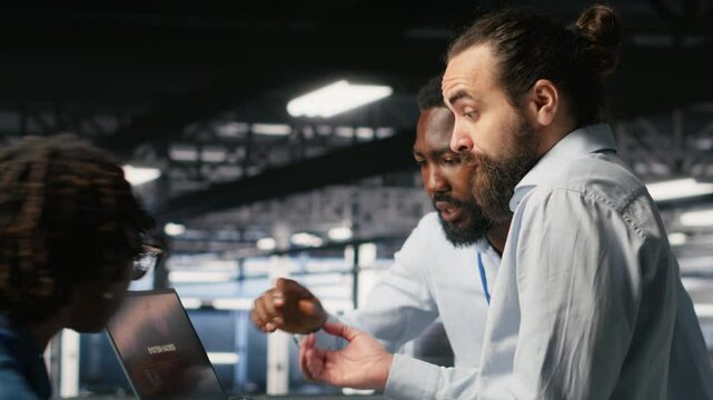 Stressed technicians in server room fighting each other after detecting hacking attempt targeting critical systems. Engineering team members under pressure by virus activity arguing, camera B