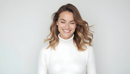 Obraz premium A woman with a warm, genuine smile and light brown wavy hair, dressed in a comfortable white turtleneck sweater, exudes confidence and happiness. Her expression is one of pure joy and contentment.
