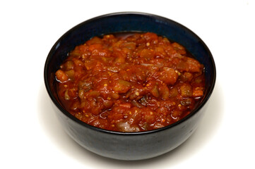 Stewed eggplant with vegetables in dark plate on white background