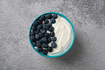 Top view of fresh blueberries on creamy yogurt in a blue bowl