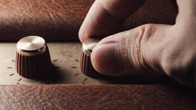 Close-up of a hand delicately tuning a vintage volume wheel, evoking nostalgia and craftsmanship. Perfect for retro, music, or tech-themed projects