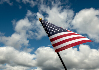 American flag against blue sky and white clouds.